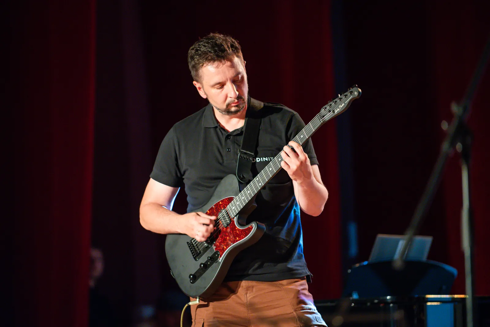 Dorosły uczeń gra na gitarze podczas koncertu szkoły