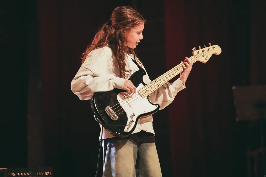 Uczennica grająca na gitarze basowej na scenie